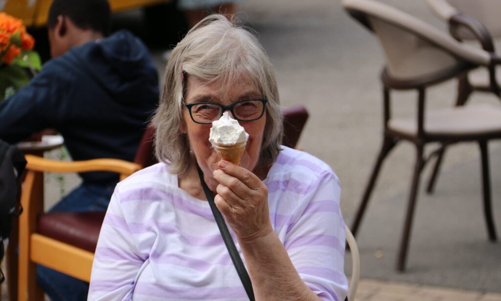 Smiling resident receiving an ice cream from a colourful ice cream van parked outside.