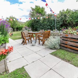 A backyard garden with a round wooden table and armchairs for residents at Roseway House care home