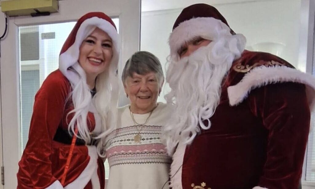 Florence Gorgan House resident standing next to Mr and Mrs Clause