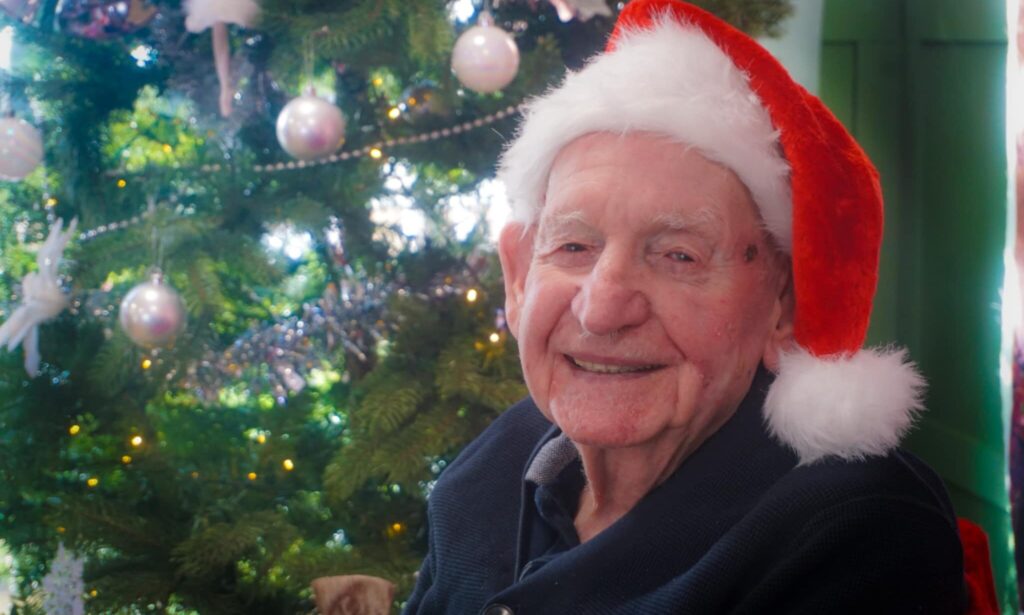 Garswood House resident smiling wearing a Christmas hat