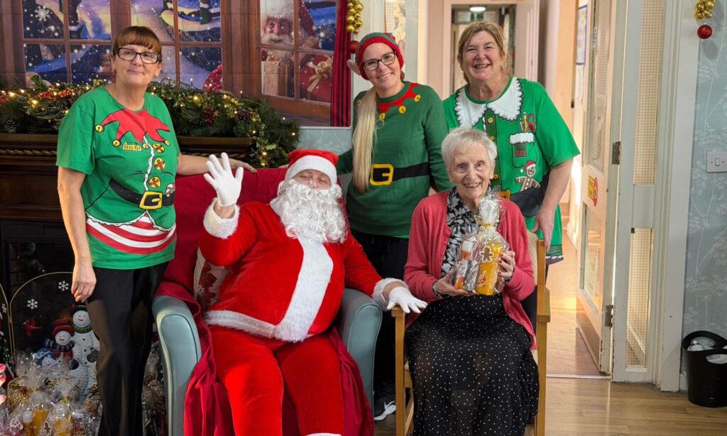 Holcroft Grange resident accepting a gift from Santa and his elves